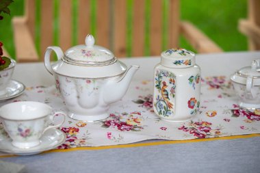 Çiçekli bir masa koşucusuyla birlikte bir çay seti bir masada sergilenir. Masa çay partisi için hazırlandı, fincanlar, çay tabakları ve çaydanlık. Masa koşucusu biraz renk katar