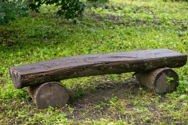 Her iki tarafında kütükler olan ahşap bir bank. Bankta çimenlik bir alan var. Yedek kulübesi ahşaptan yapılmıştır ve kırsal bir görünüşü vardır.