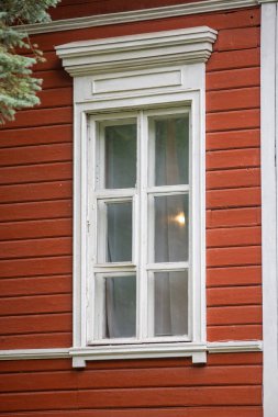 Beyaz çerçeveli ve kırmızı duvarlı bir pencere. Pencere açık ve perdeler kapalı.