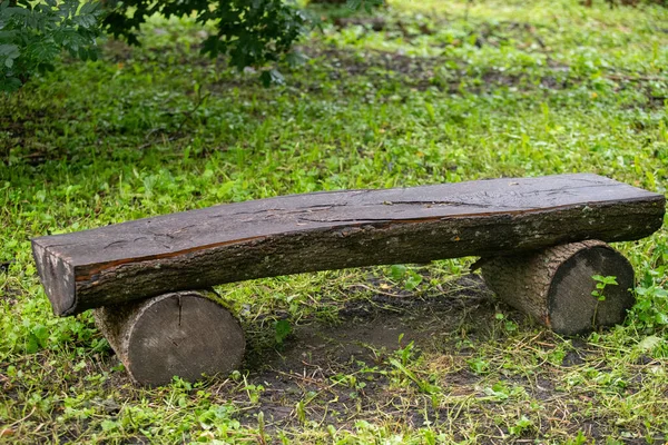Her iki tarafında kütükler olan ahşap bir bank. Bankta çimenlik bir alan var. Yedek kulübesi ahşaptan yapılmıştır ve kırsal bir görünüşü vardır.
