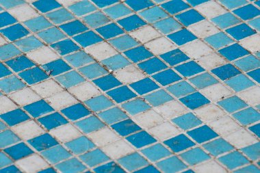 A blue and white tile floor with a pattern of squares. The tiles are dirty and worn, giving the floor a worn and aged appearance