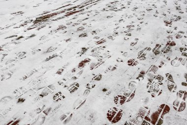 Bir sürü ayak iziyle kaplı bir kar. Ayak izleri farklı boyutlarda ve şekillerde. Hareket ve aktivite kavramı, sanki biri karda yürümüş gibi.