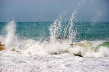 Okyanus dalgalı ve dalgalar yüksek. Su beyaz ve gökyüzü mavi.