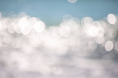 Görüntü bulanık, bulanık bir okyanus manzarası. Su sakin ve huzurlu görünüyor, görünür dalgalar ya da dalgalanmalar yok. Gökyüzü koyu mavi bir renktir ve güneş parlak bir şekilde parlar.