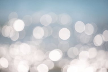 Görüntü bulanık, bulanık bir okyanus manzarası. Su sakin ve huzurlu görünüyor, güneş yüzeyden yansıyor. Sahne sakin ve sakin.