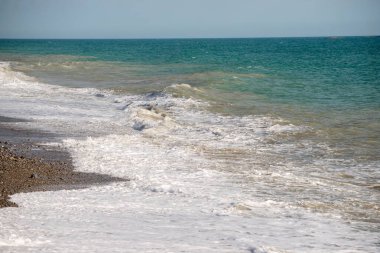 Okyanus sakin ve su mavinin güzel bir tonu. Kumsal kayalıktır ve dalgalar yumuşaktır