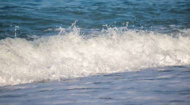 Okyanus dalgaları kıyıya çarpıyor, güzel ve rahatlatıcı bir manzara yaratıyor. Su koyu mavi bir renktir ve plajdaki kayalar manzaraya biraz doku katar.