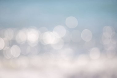 Görüntü bulanık, bulanık bir okyanus manzarası. Su sakin ve huzurlu görünüyor, görünür dalgalar ya da dalgalanmalar yok. Gökyüzü koyu mavi bir renktir ve güneş parlak bir şekilde parlar.