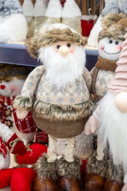 Şapkalı ve sakallı bir Noel Baba bir kardan adamın yanında duruyor. Kardan adam gülümsüyor ve boynunda eşarp var.