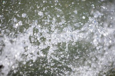 A large amount of water splashing and spraying in the air. The water droplets are scattered all over the scene, creating a sense of movement and energy. Scene is dynamic and lively