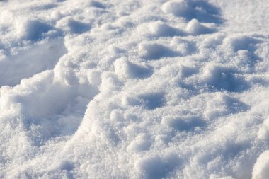 Kar beyaz ve kabarık, zemini kaplıyor. Kar bir şekilde dağ gibi yığılmış durumda.