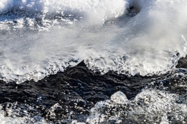 Üstünde buz yüzen bir su kütlesi. Su sakin görünüyor, buz sakin ve huzurlu bir atmosfer yaratıyor. Soğuk, donmuş buz ve sıcak arasındaki zıtlık