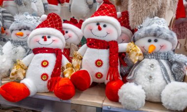 Kırmızı eşarplı ve şapkalı bir dizi kardan adam. Kardan adamlar gülümsüyor ve mutlu görünüyorlar.