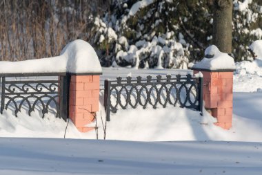 Kırmızı tuğla tabanlı bir çit karla kaplıdır. Çit karlı bir bölgede.