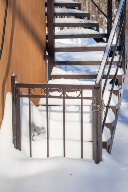 Bir kapı karla kaplıdır ve kilitlidir. Kapı bir merdivenin üzerinde.