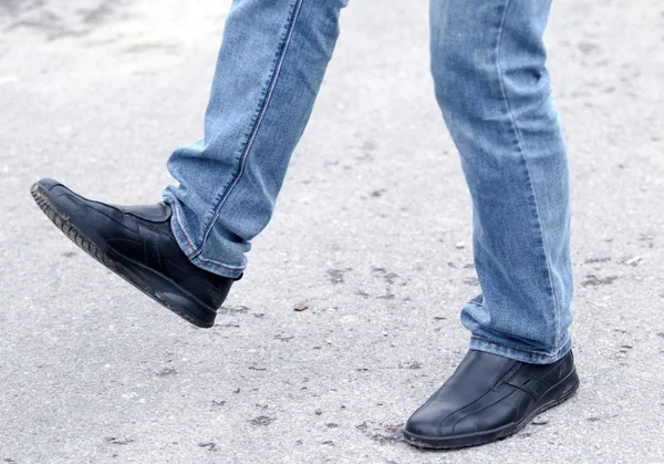 Pés de homem em jeans azul em sapatos de perto, em movimento — Fotografia de Stock