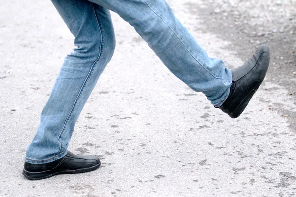 Pés de homem em jeans azul em sapatos de perto, em movimento — Fotografia de Stock