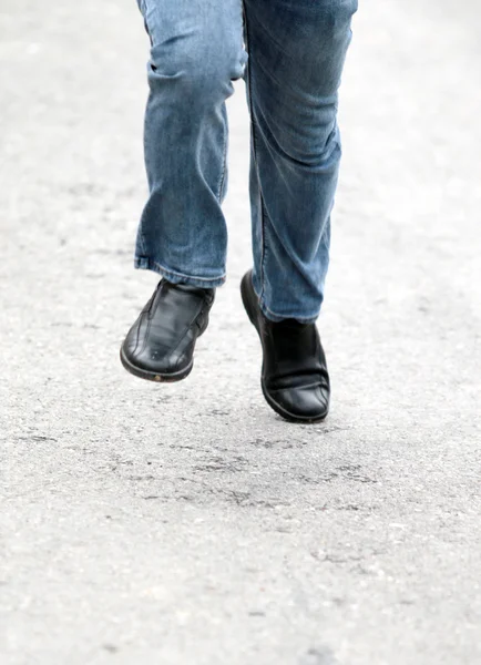 Pés de homem em jeans azul em sapatos de perto, em movimento — Fotografia de Stock