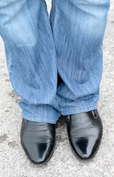 Man\'s feet in blue jeans in shoes close up, set in motion