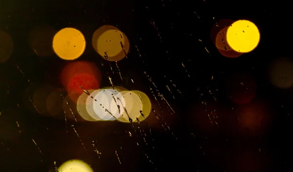 Lumière abstraite de la ville de nuit et bokeh à travers le pare-brise de voiture couvert de pluie — Photo