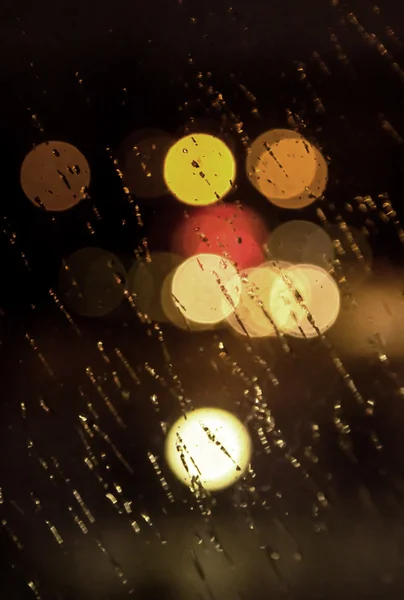 Abstract night city light and bokeh through car windscreen covered in rain — Stock Photo, Image