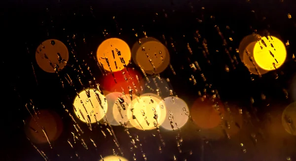 Streszczenie w nocy miasto światła i bokeh przez szyby samochodu pokryte w deszczu — Zdjęcie stockowe