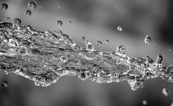 Water spuiten op een donkere achtergrond — Stockfoto