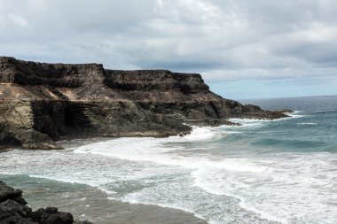 Puertito beach de los Molinos Fuerteventura üzerinde bir kayaya üzerine sıçramasına el salla. Kanarya Adaları, İspanya