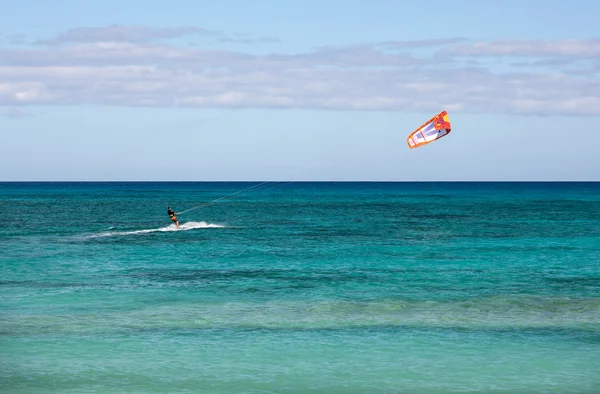 Onbekende kitesurfer surfen op een plat azuurblauwe water van de Atlantische Oceaan in Corralejo, Fuerteventura, Canarische eilanden, Spanje — Stockfoto