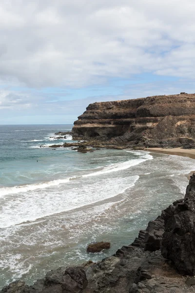 Fala, rozpryskiwania nad kamieniem na plaży Puertito de los Molinos na wyspie Fuerteventura. Wyspy Kanaryjskie, Hiszpania — Zdjęcie stockowe