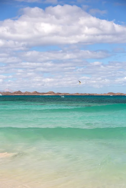 Unknown kitesurfer surfing on a flat azure water of Atlantic ocean in Corralejo, Fuerteventura, Canary islands, Spain