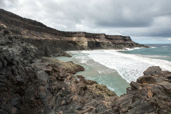 Vague éclaboussant un rocher sur la plage de Puertito de los Molinos sur Fuerteventura. Îles Canaries, Espagne — Photo