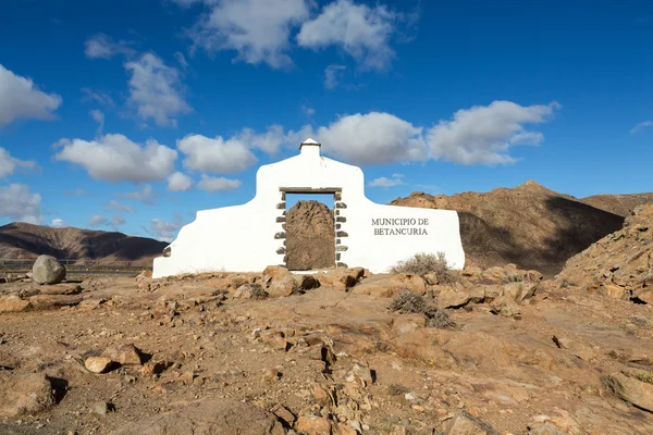 Typisches Gemeindeschild (weißes Bogentor) in der Nähe des Betancuria-Dorfes mit Wüstenlandschaft im Hintergrund, fuerteventura — Stockfoto
