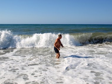Üst düzey bir adam dalga deniz Chania plajında duruyor. Crete Adası,