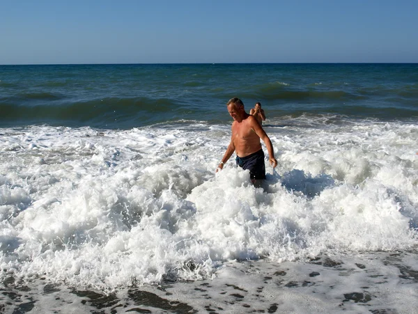Un hombre mayor está parado en la ola del mar en la playa de Chania. Isla de Creta , — Foto de Stock