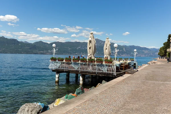 Jezero Garda s promenádou a restaurace v obci Torri del Benaco, Itálie — Stock fotografie