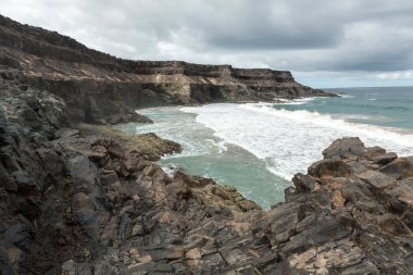 Puertito beach de los Molinos Fuerteventura üzerinde bir kayaya üzerine sıçramasına el salla. Kanarya Adaları, İspanya