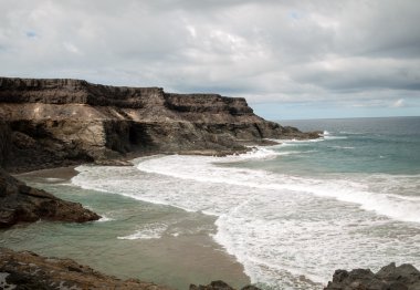 Puertito beach de los Molinos Fuerteventura üzerinde bir kayaya üzerine sıçramasına el salla. Kanarya Adaları, İspanya