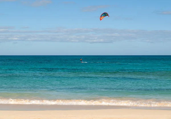 Onbekende kitesurfer surfen op een plat azuurblauwe water van de Atlantische Oceaan in Corralejo, Fuerteventura, Canarische eilanden, Spanje — Stockfoto