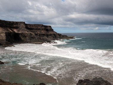 Puertito beach de los Molinos Fuerteventura üzerinde bir kayaya üzerine sıçramasına el salla. Kanarya Adaları, İspanya