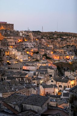 Matera 'daki antik Sassi bölgesinde geceleri, antik mağara evleri ile tanınan şaşırtıcı aydınlık binalar. Basilicata. İtalya