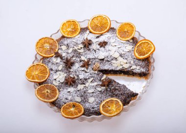 Haşhaş tohumlu tart ve üzerine toz şeker serpiştirilmiş meyve.