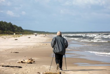 Aktif, olgun yaşam tarzı. Yaşlı İskandinav kumlu sahil kıyısında yürüyor