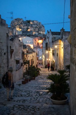 Matera, İtalya - 15 Eylül 2019: Matera şehrinin tarihi bir bölgesi olan Sassi di Matera 'daki Cobblestone caddesinde yürüyüş yapan turistler. Basilicata. İtalya