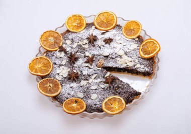 Haşhaş tohumlu tart ve üzerine toz şeker serpiştirilmiş meyve.