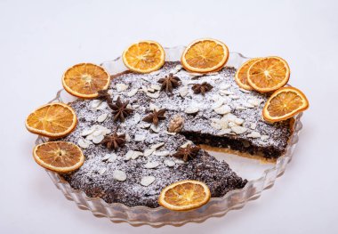 Haşhaş tohumlu tart ve üzerine toz şeker serpiştirilmiş meyve.