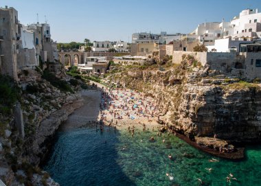 Polignano, İtalya - 17 Eylül 2019: İnsanlar Polignano a Mare, Adriyatik Denizi, Apulia, Bari ili, İtalya 'daki sevimli Lama Monachile plajında dinleniyor ve yüzüyorlar,