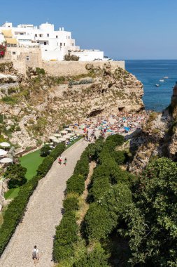 Polignano, İtalya - 17 Eylül 2019: İnsanlar Polignano a Mare, Adriyatik Denizi, Apulia, Bari ili, İtalya 'daki sevimli Lama Monachile plajında dinleniyor ve yüzüyorlar,