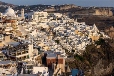 Fira, Santorini, Yunanistan - 27 Haziran 2021: Yunanistan 'ın Kiklad adasındaki Santorini Adası' nda gün batımının ılık ışınlarında beyazlatılmış Fira kasabası