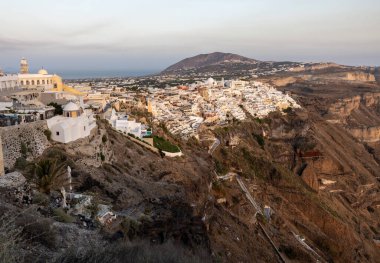 Yunanistan 'ın Kiklad adasındaki Santorini Adası' nda beyazlatılmış Fira kasabası gün batımının ılık ışınlarıyla